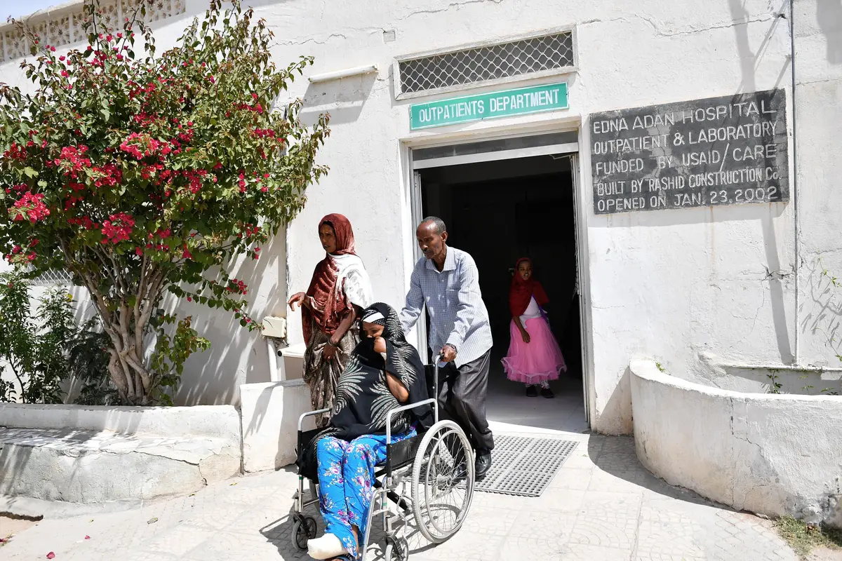 A caretaker helps a patient in a wheelchair outside a hospital entrance in Hargeisa